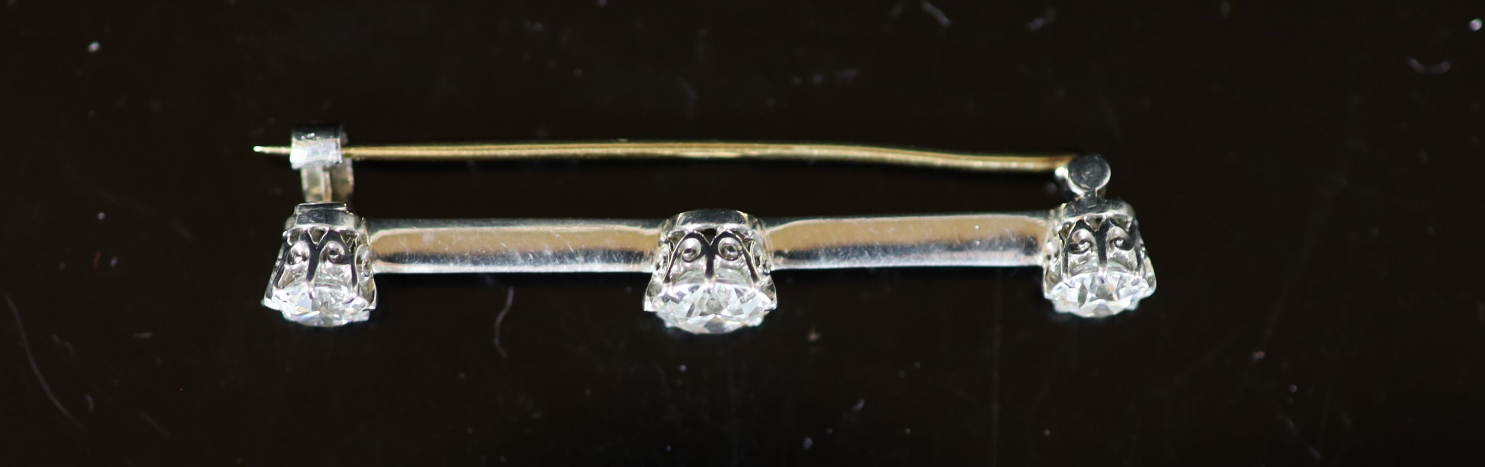A gold, platinum and three stone diamond set bar brooch